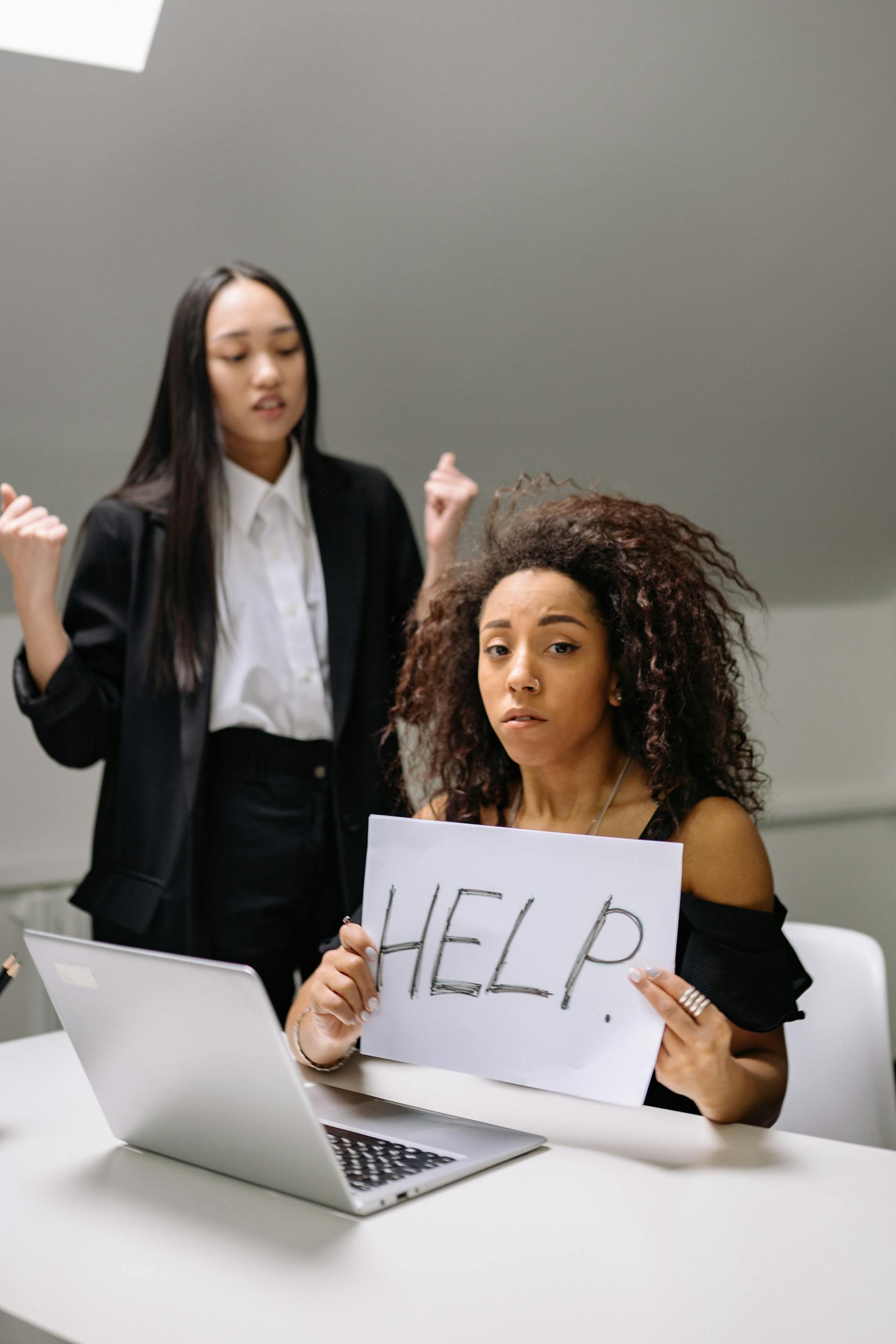 A woman holding a help sign, depicting workplace harassment in an office setting.